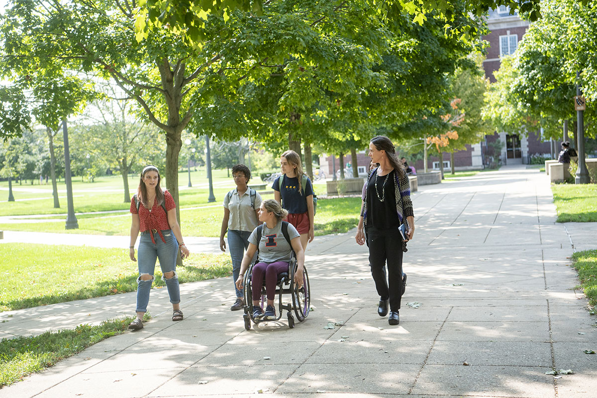 Students strolling through campus under trees