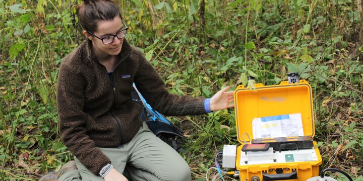 Person sitting on the ground with a box of equipment