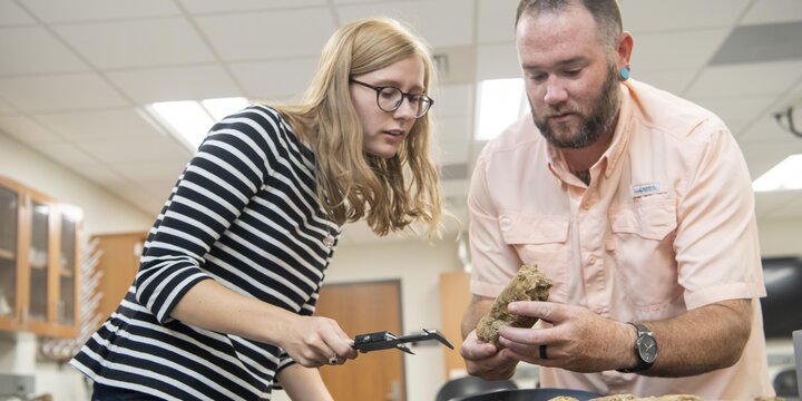 Professor examining soil with their student.