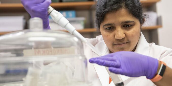 Student in a lab with a pipette in hand, testing out soil in a test tube
