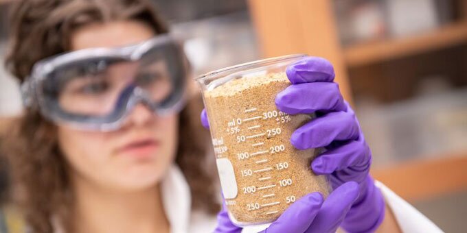 Student examining soil sample in lab.
