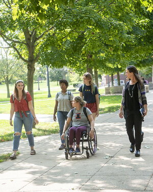 Students touring campus along sidewalk under trees on a sunny day